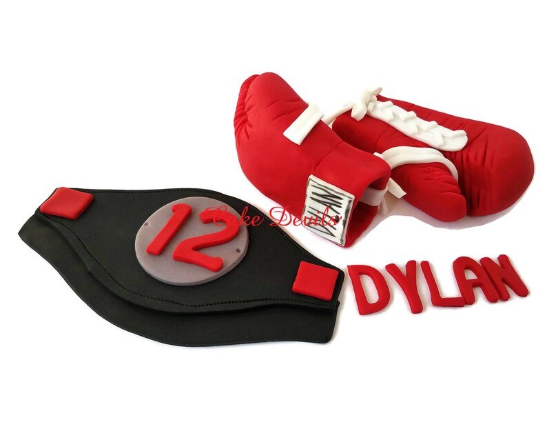 May include: Red boxing gloves with white laces and a black championship belt with the number 12 on it. The name Dylan is spelled out in red letters.