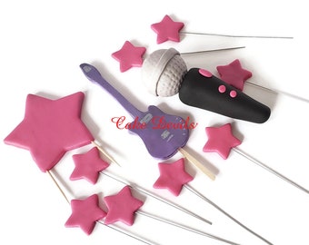 May include: A set of cake toppers featuring a purple electric guitar, a black microphone, and pink stars. The toppers are on thin wires for easy placement on a cake.