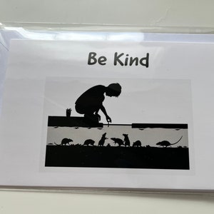 Puede incluir: Una ilustración en blanco y negro de una persona ofreciendo comida a un grupo de ratas. La imagen está en una tarjeta blanca con el texto "Be Kind" en la parte superior.