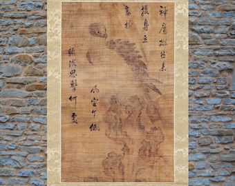 Op de afbeelding: Een rechthoekige wandhanger met een bruine inkttekening van een valk op een rots. Het kunstwerk is omgeven door een decoratieve beige bloemenrand en bevat verticale kolommen met zwarte Chinese kalligrafiekarakters.