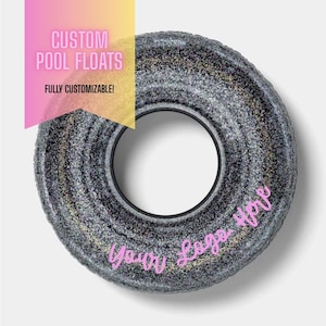 May include: A custom pool float with a glittery, dark gray exterior and a black inner tube. The text "CUSTOM POOL FLOATS" and "FULLY CUSTOMIZABLE!" are displayed on a pink and yellow banner. The words "Your Logo Here" are in pink script.