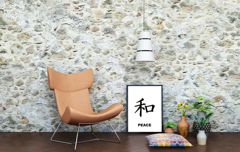 May include: A brown leather armchair with a metal frame sits in front of a stone wall. A black framed print with the Japanese character for peace and the word "peace" below it hangs on the wall. There are potted plants and a colorful throw pillow on the floor.