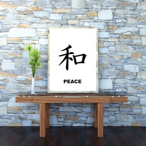 May include: A white framed print with the Japanese character for peace, "和", and the word "PEACE" written below it. The print is hanging on a stone wall above a wooden table.