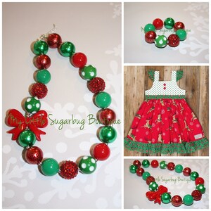 May include: A red and green Christmas-themed necklace with a red bow and white polka dots. The necklace is made of large, chunky beads. The necklace is also available as a bracelet.