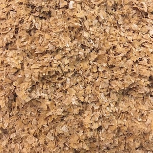 May include: A close-up of a pile of light brown wheat flakes. The flakes are small and irregular in shape, and they have a slightly rough texture.