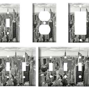 May include: Set of six black and white light switch and outlet covers featuring a cityscape of New York City.