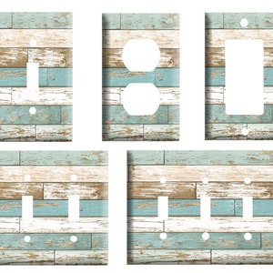 May include: Set of five light switch and outlet covers featuring a distressed wood plank design in shades of blue, white, and brown.