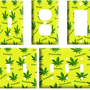 May include: Four light switch covers with a yellow background and a green marijuana leaf pattern. The text "Cannabis" is repeated throughout the pattern.
