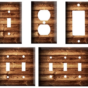 May include: Set of four light switch and outlet covers featuring a rustic woodgrain design. The covers are in various sizes and configurations, including a single switch, a double switch, a triple switch, and an outlet.