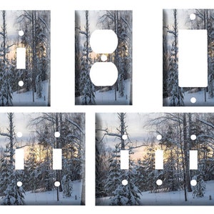 May include: A set of six light switch and outlet covers featuring a wintery scene of snow-covered trees and a sunrise. The covers are available in a variety of sizes and styles to fit your needs.