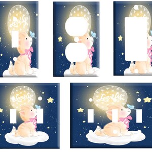 May include: A set of four light switch and outlet covers featuring a cute cartoon cat holding a balloon that says "Lovely". The background is a dark blue with white stars.