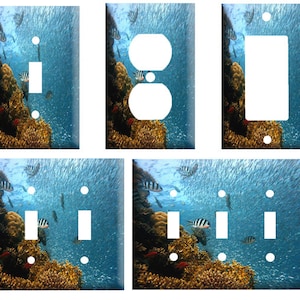 May include: A set of light switch and outlet covers featuring a colorful underwater scene with coral reefs and fish. The covers are available in various configurations, including single, double, and triple switch options.
