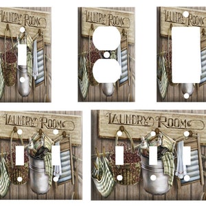 May include: Set of five decorative light switch covers featuring a rustic laundry room theme. The covers feature a wooden sign with the text "Laundry Room", a bucket, a basket, and a wringer. The covers are available in a variety of sizes to fit standard light switches and outlets.