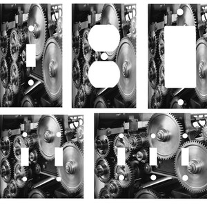 May include: A set of six black and white light switch and outlet covers featuring a close-up image of a machine with interlocking gears.