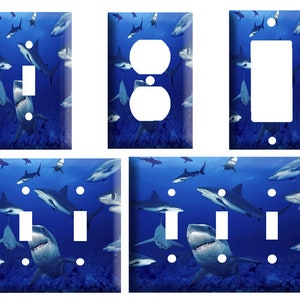 May include: A set of five light switch and outlet covers featuring a blue ocean scene with sharks swimming. The covers are made of durable plastic and are easy to install.