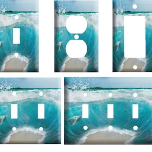 May include: A set of light switch and outlet covers featuring a beach scene with turquoise water, white waves, and a sea turtle swimming through the water.