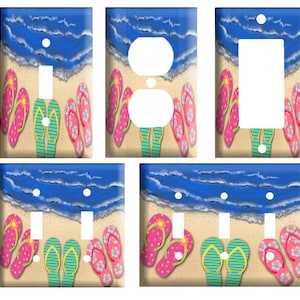 May include: Set of four light switch and outlet covers featuring a beach scene with flip flops on the sand. The covers are available in single, double, and triple switch configurations.