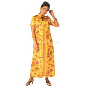 May include: A floor-length yellow dress featuring a short-sleeved overlay with a mandarin collar and a dark brown floral print. The garment has a central slit down the front, revealing a solid yellow underlayer, and a dark brown decorative toggle closure.