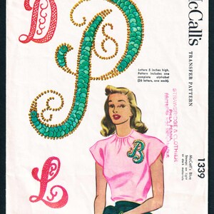 May include: Vintage McCall's transfer pattern featuring decorative alphabet designs for sequins and beads. The letters are 5 inches high. The image includes a woman wearing a pink top with a sequined letter "B".