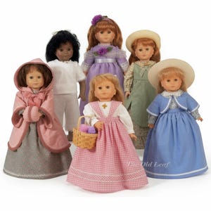 May include: A collection of six dolls dressed in various outfits, including a pink hooded cloak, a white blouse and pants, a purple dress, a green dress with a straw hat, a pink gingham dress with a basket, and a blue dress with a straw hat.