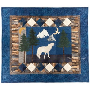 May include: A handcrafted quilt featuring a central scene of a howling wolf under a night sky with trees and mountains. The quilt has a blue border with a log cabin-style design and diamond accents. The Old Leaf is printed on the bottom right.