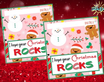 Könnte beinhalten: Zwei rosa und grüne Weihnachtsgeschenkanhänger mit einem Schneemann, einem Lebkuchenmann und Geschenken. Der Text auf den Anhängern lautet "Ich hoffe, dein Weihnachten rockt".