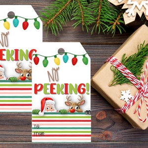 May include: Two white gift tags with a red and green striped background. The tags feature a Santa and a reindeer peeking over the top of the stripes. The text on the tags reads "No Peeking!" with colorful Christmas lights above the text. The tags have a hole punched in the top for string.
