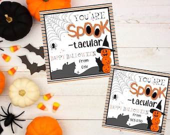Può includere: Due etichette regalo di Halloween stampabili con sfondo a strisce nero e arancione. Le etichette presentano un gatto nero, un cappello da strega e una pila di zucche. Il testo sulle etichette recita "You are Spook-tacular" e "Happy Halloween".