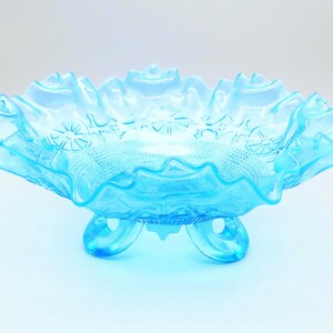 Könnte beinhalten: Eine hellblaue Glasschale mit gewelltem Rand und drei Füßen. Die Schale hat ein detailliertes Muster aus Sternen und anderen Formen. Die Schale ist wahrscheinlich Vintage. Die Maße der Schale sind in Zentimetern.