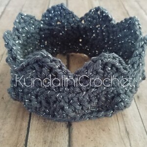 May include: A dark gray crocheted crown with silver glitter thread. The crown is made with a simple stitch pattern and has a scalloped edge.