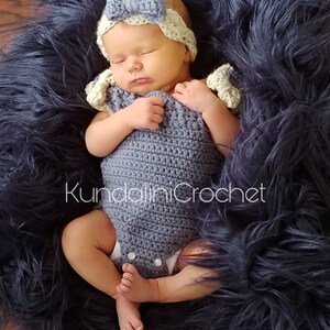 May include: A baby wearing a crocheted blue and white outfit with a white crocheted headband. The baby is lying on a blue fuzzy blanket.