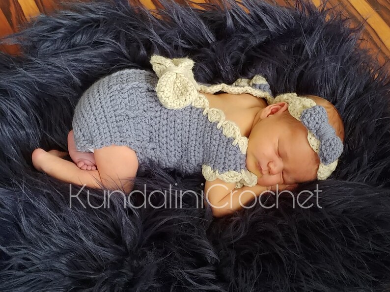 May include: A sleeping baby wearing a crocheted gray and white outfit with a matching headband. The baby is lying on a black fuzzy surface. The text "Kundalini Crochet" is visible in the image.