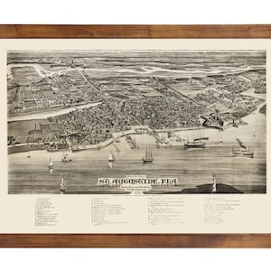 May include: A vintage black and white bird's eye view map of St. Augustine, Florida, from 1884. The map shows the city's layout, including its streets, buildings, and waterways. The map is framed in a brown wooden frame.