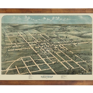 May include: An antique framed map of Brenham, Washington County, Texas. The map is an aerial view of the town, with streets and buildings visible. The map is in shades of green, brown, and beige, with a wooden frame.