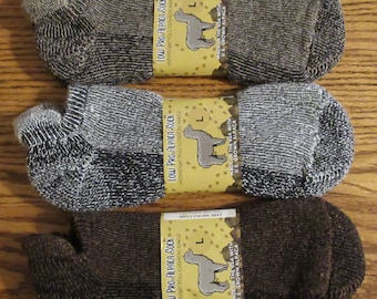 May include: Three pairs of rolled-up ankle socks in shades of brown and grey, each with a label. The labels read "Low Pro Alpaca Sock" and feature a drawing of an alpaca. The socks are made in the USA with US grown alpaca.