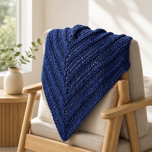 Könnte beinhalten: Ein tiefblaues, dreieckiges Tuch mit einem markanten Chevron-Strickmuster. Das gestrickte Textil weist ein strukturiertes Rippendesign mit V-förmiger Ausrichtung auf und zeigt ein gleichmäßiges Garnbild sowie eine satte, marineblaue Farbgebung.