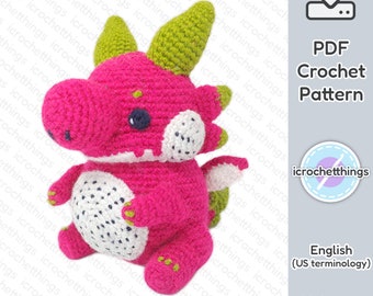 Puede incluir: Un patrón de crochet para un amigurumi de dragón rosa. El dragón tiene cuernos verdes y una barriga blanca y negra. El patrón está disponible para descargar en PDF.