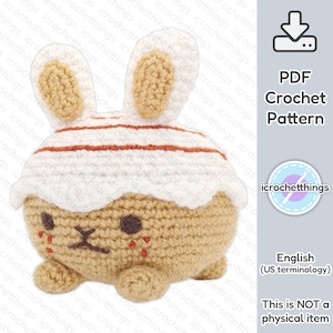 Puede incluir: Un patrón de crochet para un conejito marrón y blanco con un gorro blanco y rojo a rayas. El patrón está disponible para descargar en PDF. El texto "Esto NO es un artículo físico" también está incluido en la imagen.