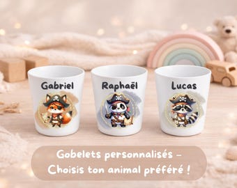 Può includere: Tre bicchieri di plastica bianchi con illustrazioni di animali pirata. Il bicchiere a sinistra mostra una volpe con il nome Gabriel, quello centrale un panda con Raphaël e quello a destra un procione con il nome Lucas.