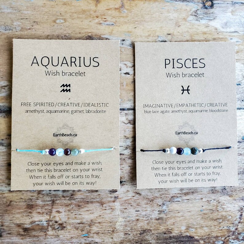 May include: Two cards featuring the zodiac signs Aquarius and Pisces. Each card displays a wish bracelet with assorted coloured beads and a description of the zodiac sign's personality traits. The text on the cards reads "Aquarius Wish Bracelet" and "Pisces Wish Bracelet".