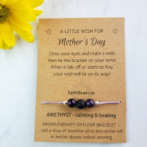 May include: A brown card with the text "A Little Wish For Mother's Day" and instructions for a wish bracelet. The bracelet is made with purple amethyst beads, black lava beads, and a silver bead. The bracelet is tied with a light purple string.