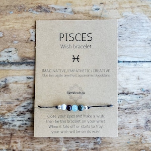 May include: A brown card with the text "PISCES Wish bracelet" and the astrological symbol for Pisces. The card also includes the text "IMAGINATIVE/EMPATHETIC/CREATIVE blue lace agate, amethyst, aquamarine, bloodstone" and "EarthBeads.ca". A black string bracelet with blue, green, white, and silver beads is shown on the card. The card also includes the text "Close your eyes and make a wish, then tie this bracelet on your wrist. When it falls off or starts to fray, your wish will be on its way!"