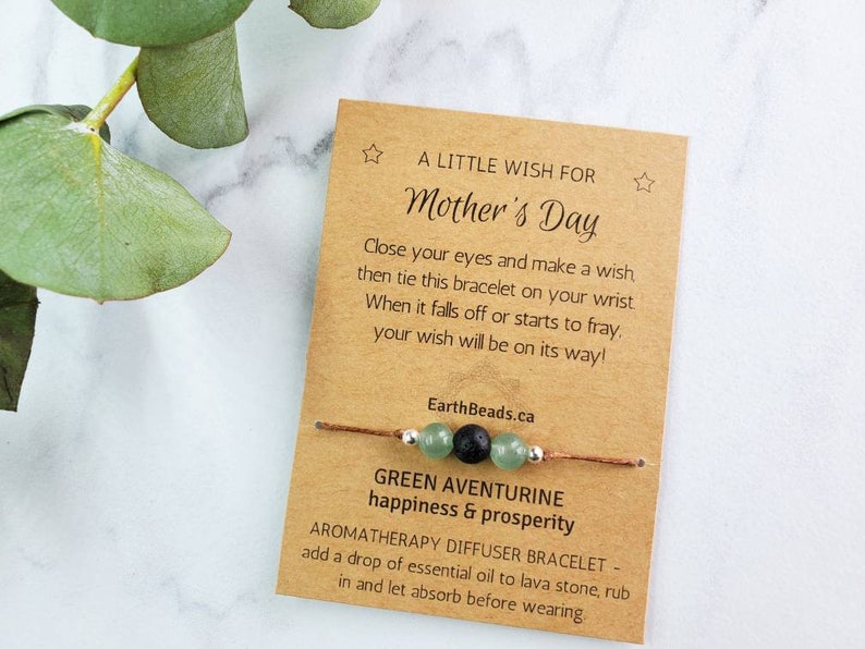 May include: A brown card with the text "A Little Wish For Mother's Day" and instructions for making a wish with a green aventurine and lava stone bracelet. The card also says "Green Aventurine happiness & prosperity" and "Aromatherapy Diffuser Bracelet - add a drop of essential oil to lava stone, rub in and let absorb before wearing."
