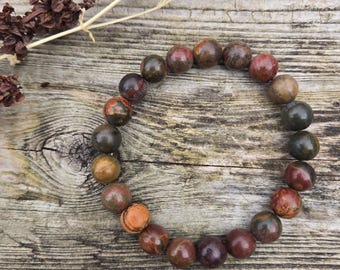 May include: A bracelet made of brown, red, and green jasper beads. The beads are round and have a natural, polished finish.