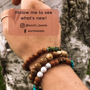 May include: A person's wrist wearing four beaded bracelets. The bracelets are made of wood, stone, and turquoise. The text "Follow me to see what's new! @earth_beads f earthbeads" is visible in the image.