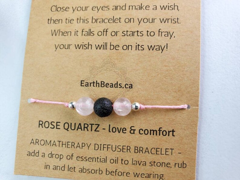 May include: Pink string bracelet with a rose quartz bead, a black lava bead, and silver spacer beads. The card reads "Close your eyes and make a wish, then tie this bracelet on your wrist. When it falls off or starts to fray, your wish will be on its way! EarthBeads.ca ROSE QUARTZ - love & comfort AROMATHERAPY DIFFUSER BRACELET - add a drop of essential oil to lava stone, rub in and let absorb before wearing."