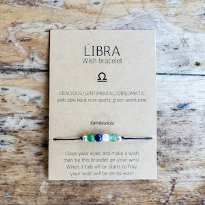 May include: A brown card with the text "LIBRA Wish bracelet" and the astrological symbol for Libra. The card also includes the text "GRACIOUS/SENTIMENTAL/DIPLOMATIC jade, lapis lazuli, rose quartz, green aventurine" and "EarthBeads.ca". A black string bracelet with green, blue, and white beads is shown on the card. The card also includes the text "Close your eyes and make a wish, then tie this bracelet on your wrist. When it falls off or starts to fray, your wish will be on its way!"