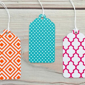 May include: Three gift tags with different geometric patterns. The first tag has a white and orange diamond pattern. The second tag has a white and teal polka dot pattern. The third tag has a white and pink quatrefoil pattern.