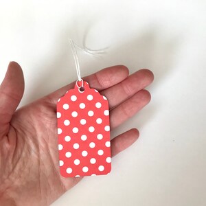 May include: A red gift tag with white polka dots and a white string attached.