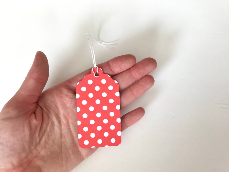 May include: A red gift tag with white polka dots and a white string attached.
